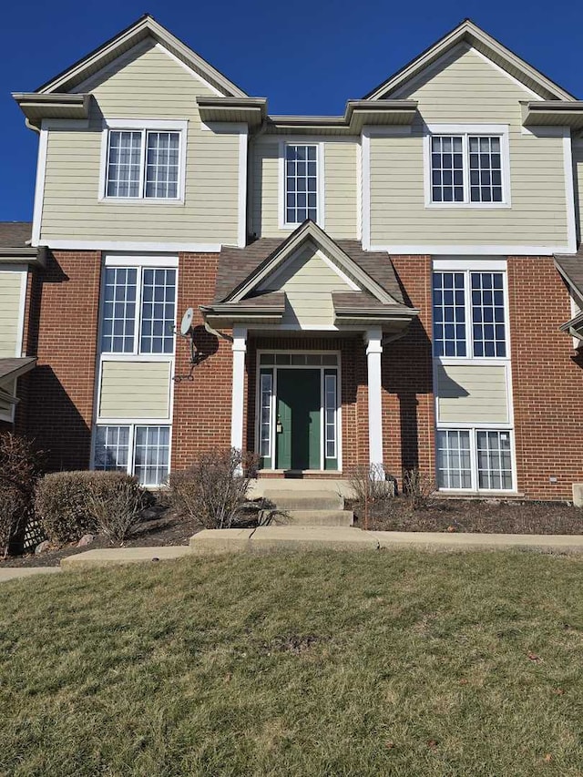 view of front facade with a front yard and brick siding