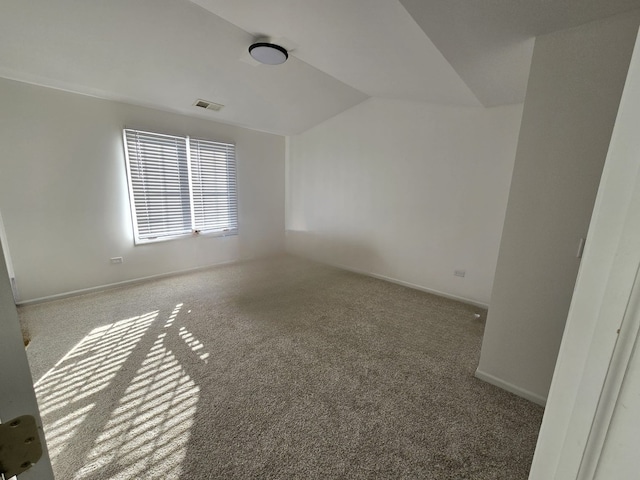 carpeted empty room with lofted ceiling, baseboards, and visible vents