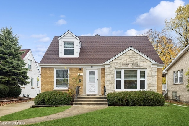 view of front of property with roof with shingles, brick siding, and a front lawn