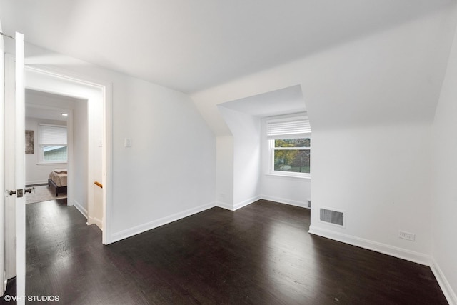 bonus room featuring dark wood-style flooring, visible vents, and baseboards