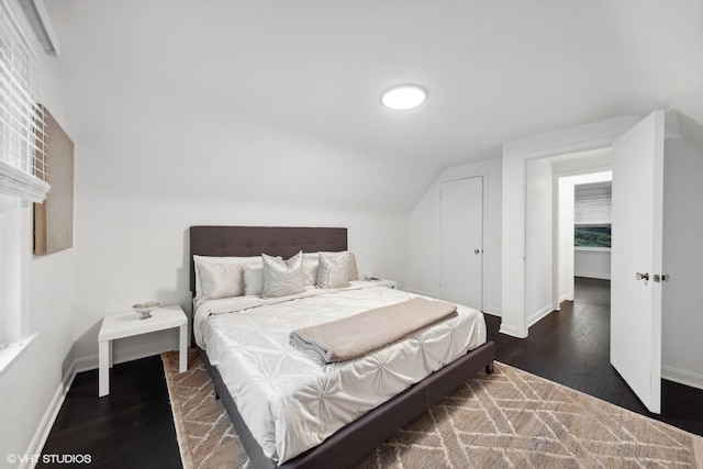 bedroom featuring lofted ceiling, dark wood-style floors, and baseboards