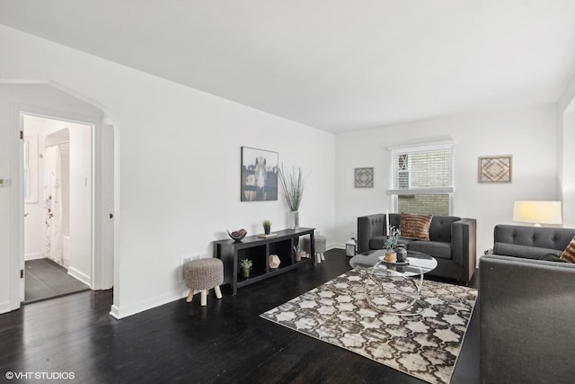 living room featuring baseboards, arched walkways, and wood finished floors