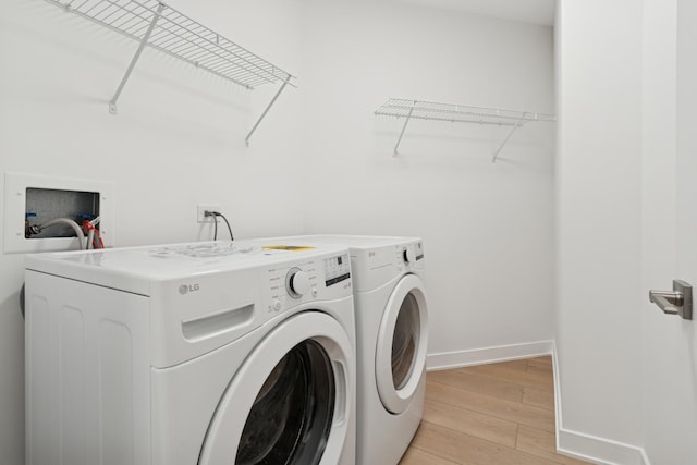 clothes washing area with light wood-type flooring, baseboards, independent washer and dryer, and laundry area