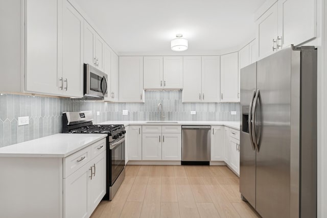 kitchen featuring a sink, backsplash, appliances with stainless steel finishes, and light countertops