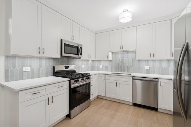 kitchen with tasteful backsplash, light countertops, stainless steel appliances, white cabinetry, and a sink