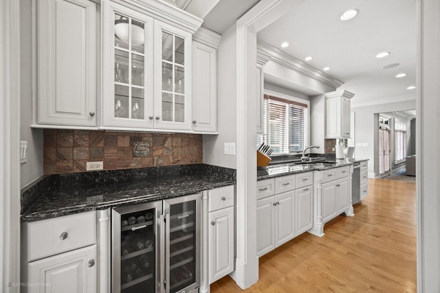 kitchen with light wood finished floors, a sink, white cabinetry, and crown molding