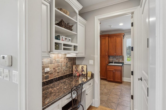 kitchen with a sink, backsplash, open shelves, dark stone countertops, and crown molding