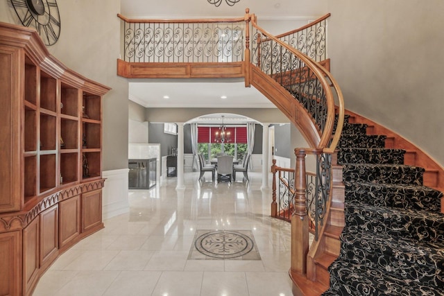 stairs with a towering ceiling, ornate columns, arched walkways, and ornamental molding