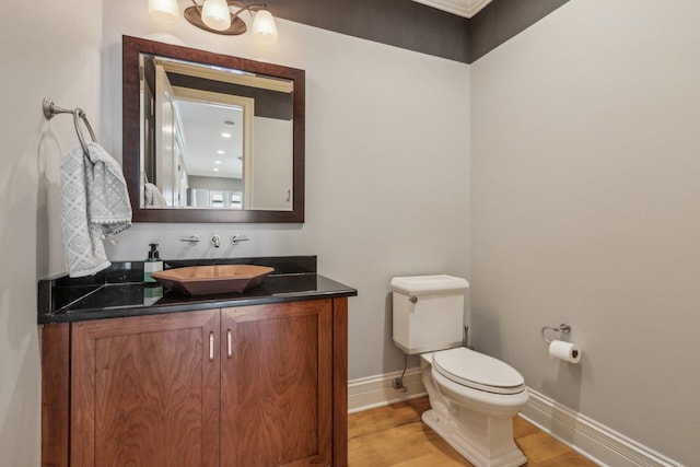 bathroom with baseboards, vanity, toilet, and wood finished floors