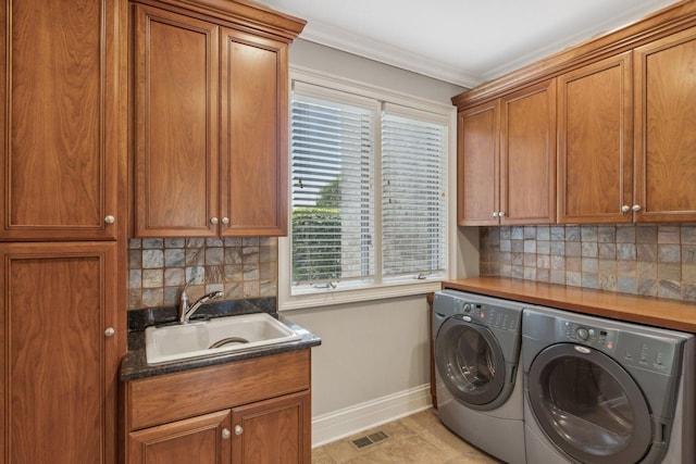 laundry area featuring cabinet space, baseboards, visible vents, washer and dryer, and a sink