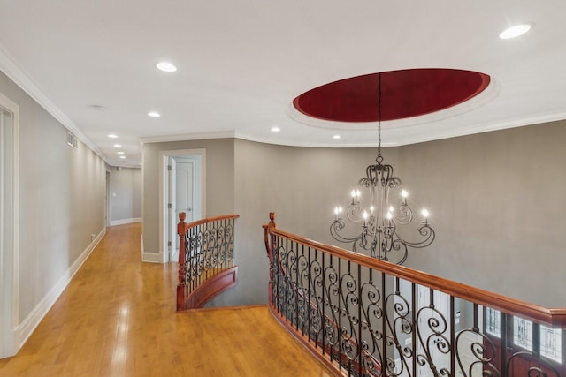 corridor featuring a notable chandelier, wood finished floors, crown molding, and an upstairs landing