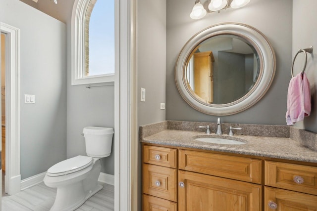 bathroom with toilet, baseboards, and vanity