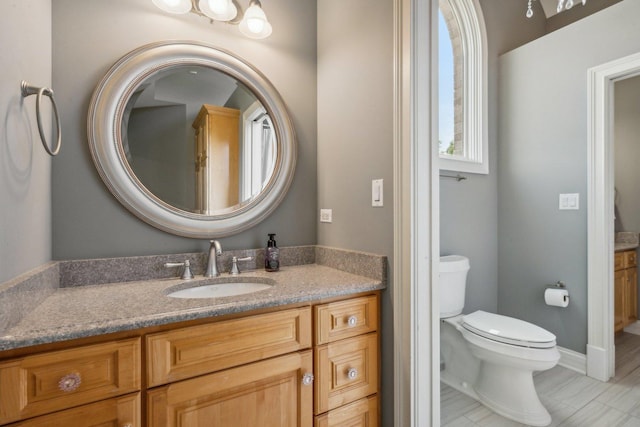 bathroom with toilet, baseboards, and vanity