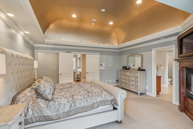 bedroom featuring ornamental molding, a tray ceiling, light carpet, and visible vents