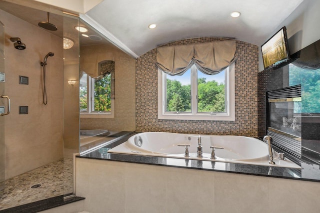 bathroom with lofted ceiling, a garden tub, plenty of natural light, and a shower stall