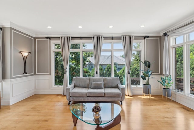 sitting room with light wood-style flooring, ornamental molding, a decorative wall, and recessed lighting