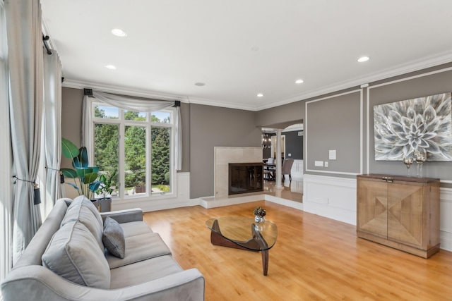 living area with light wood finished floors, a fireplace, ornamental molding, and recessed lighting