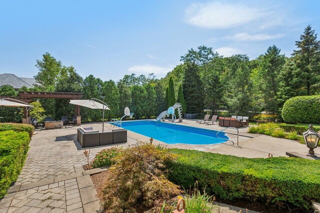 outdoor pool featuring a patio area, a pergola, a water slide, and an outdoor living space with a fire pit