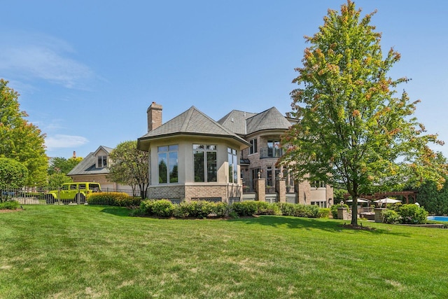 rear view of house with a chimney, fence, and a yard