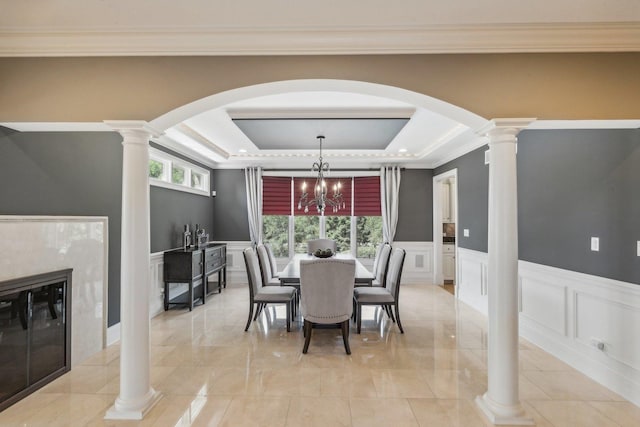 dining area featuring decorative columns, a tray ceiling, and a decorative wall