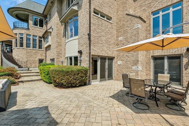 view of patio with stairs, outdoor dining area, and french doors