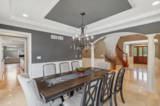 dining area with a wainscoted wall, visible vents, a tray ceiling, and arched walkways