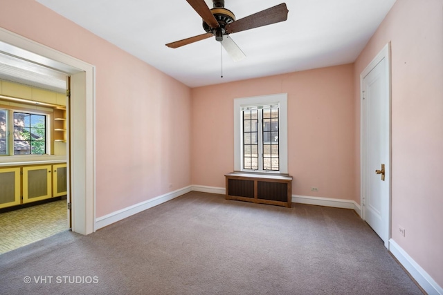 carpeted empty room with a ceiling fan and baseboards