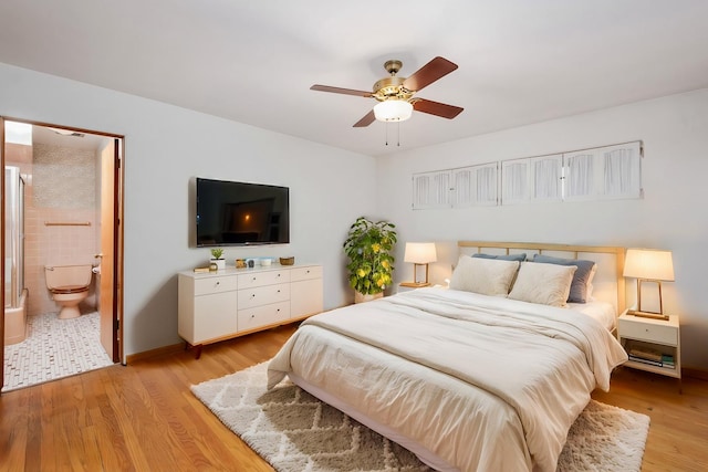 bedroom featuring light wood-style floors, a ceiling fan, baseboards, and ensuite bathroom