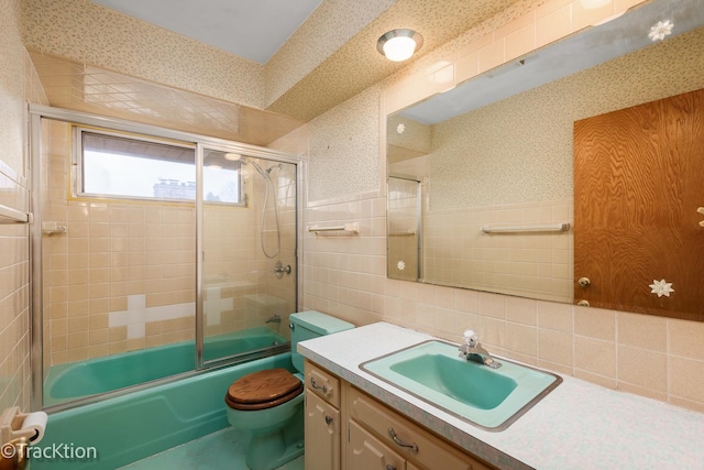 full bath with wallpapered walls, wainscoting, toilet, combined bath / shower with glass door, and tile walls