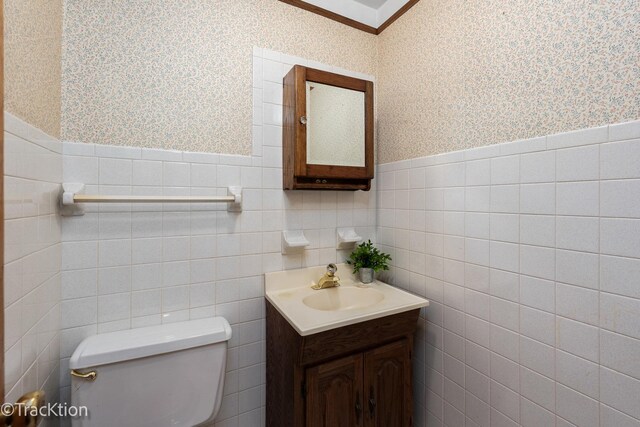 bathroom featuring wainscoting, vanity, toilet, and wallpapered walls