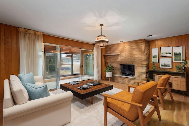 living area featuring light wood-type flooring, a brick fireplace, and wooden walls