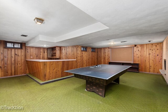 game room with a bar, carpet, wooden walls, and baseboards