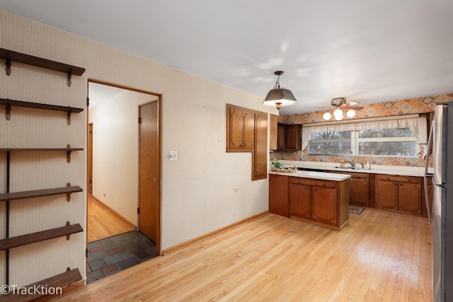 kitchen featuring brown cabinets, light wood-type flooring, freestanding refrigerator, and light countertops