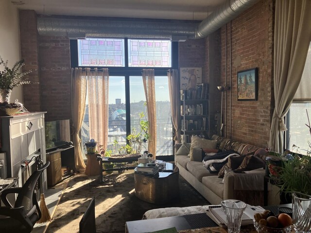 living room with brick wall, a high ceiling, and a city view