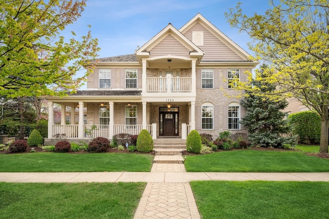 view of front of house with a balcony, a porch, and a front yard