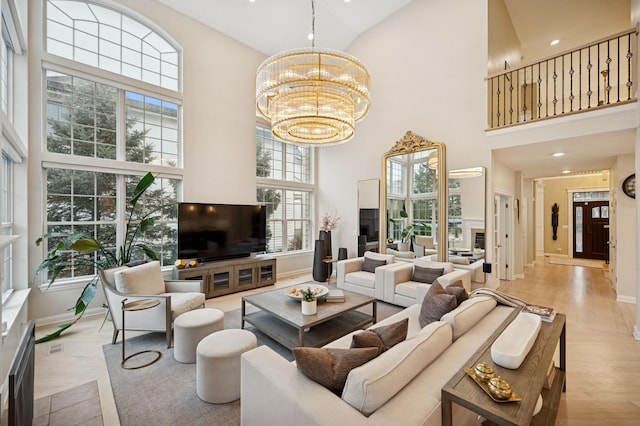 living room with baseboards, wood finished floors, a notable chandelier, and a towering ceiling