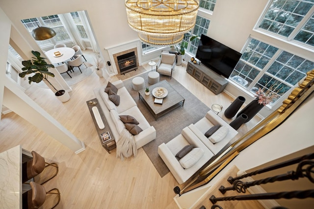 living area featuring a notable chandelier, a high ceiling, wood finished floors, and a tiled fireplace