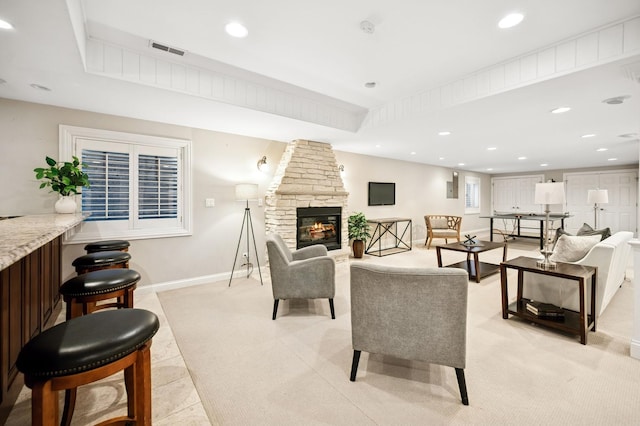 living room with recessed lighting, visible vents, baseboards, and a stone fireplace