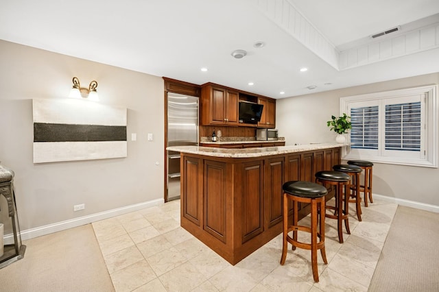 kitchen with stainless steel built in fridge, visible vents, a peninsula, baseboards, and light stone countertops