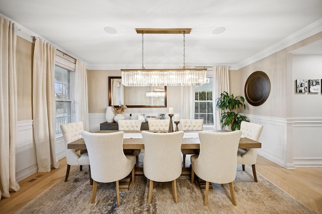 dining area featuring a wainscoted wall, wood finished floors, and ornamental molding