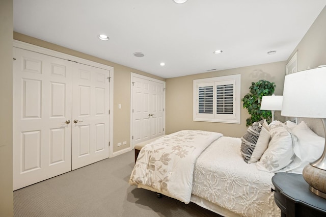 carpeted bedroom featuring recessed lighting, multiple closets, and baseboards