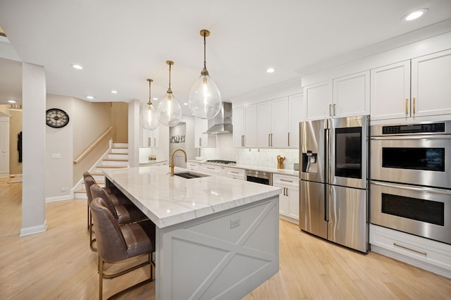 kitchen featuring a sink, wine cooler, light wood-style floors, appliances with stainless steel finishes, and wall chimney exhaust hood