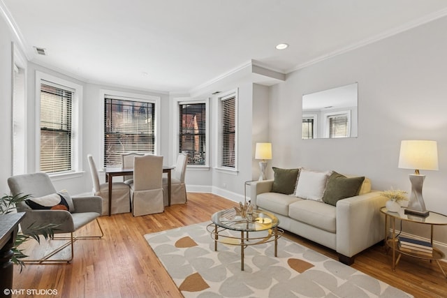 living area with visible vents, ornamental molding, a wealth of natural light, and light wood finished floors