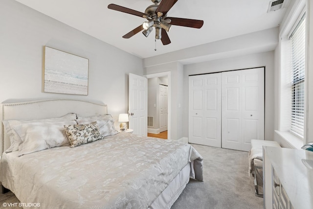 bedroom featuring visible vents, ceiling fan, a closet, and light colored carpet