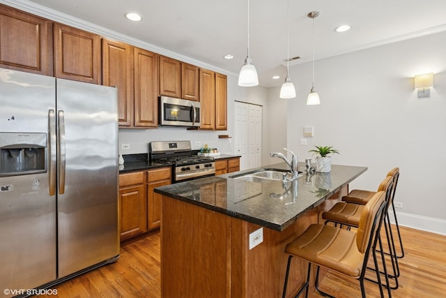 kitchen with brown cabinets, stainless steel appliances, a sink, and light wood finished floors