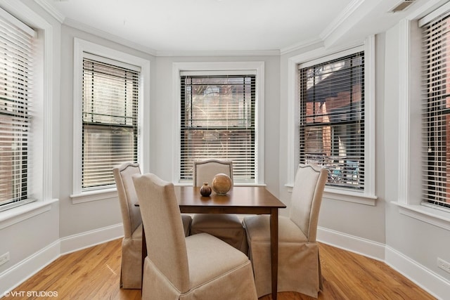 dining space with baseboards, ornamental molding, a wealth of natural light, and light wood-style floors