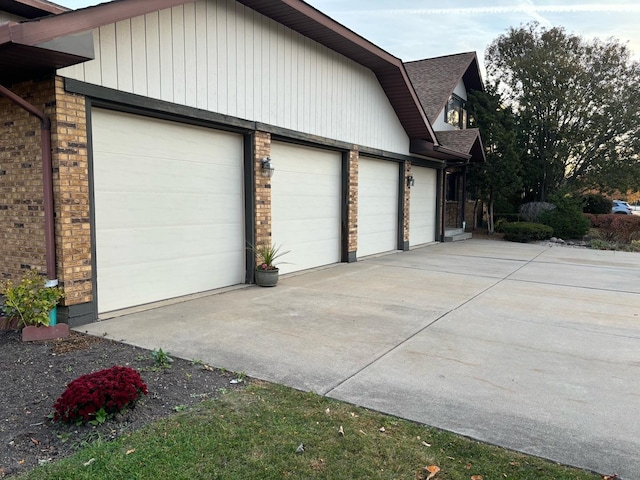view of home's exterior with a garage, brick siding, concrete driveway, and roof with shingles