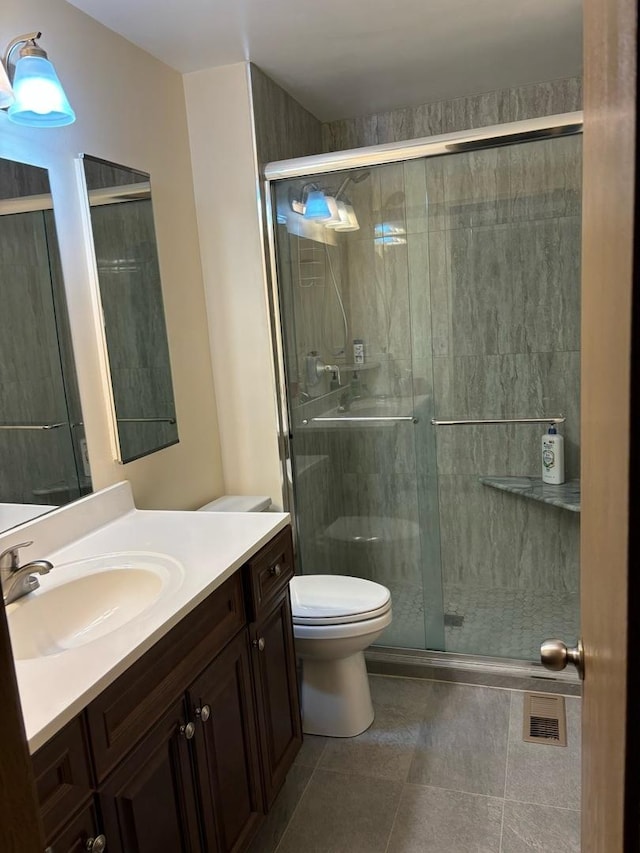 bathroom featuring vanity, toilet, a stall shower, visible vents, and tile patterned flooring