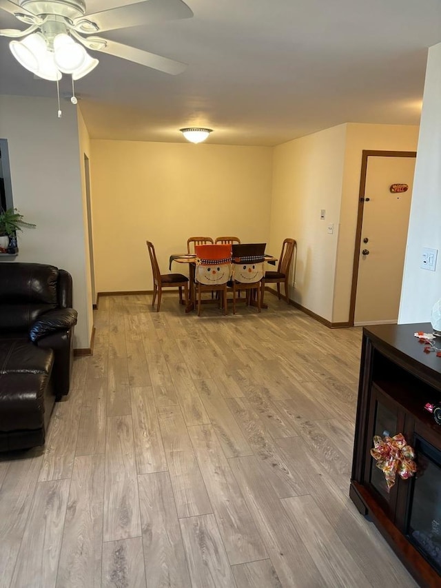 dining space with baseboards, ceiling fan, and light wood-style floors