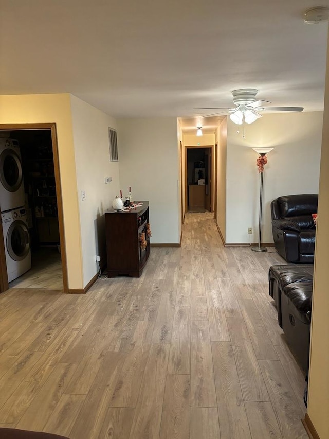 corridor with stacked washer and dryer, visible vents, light wood-style flooring, and baseboards